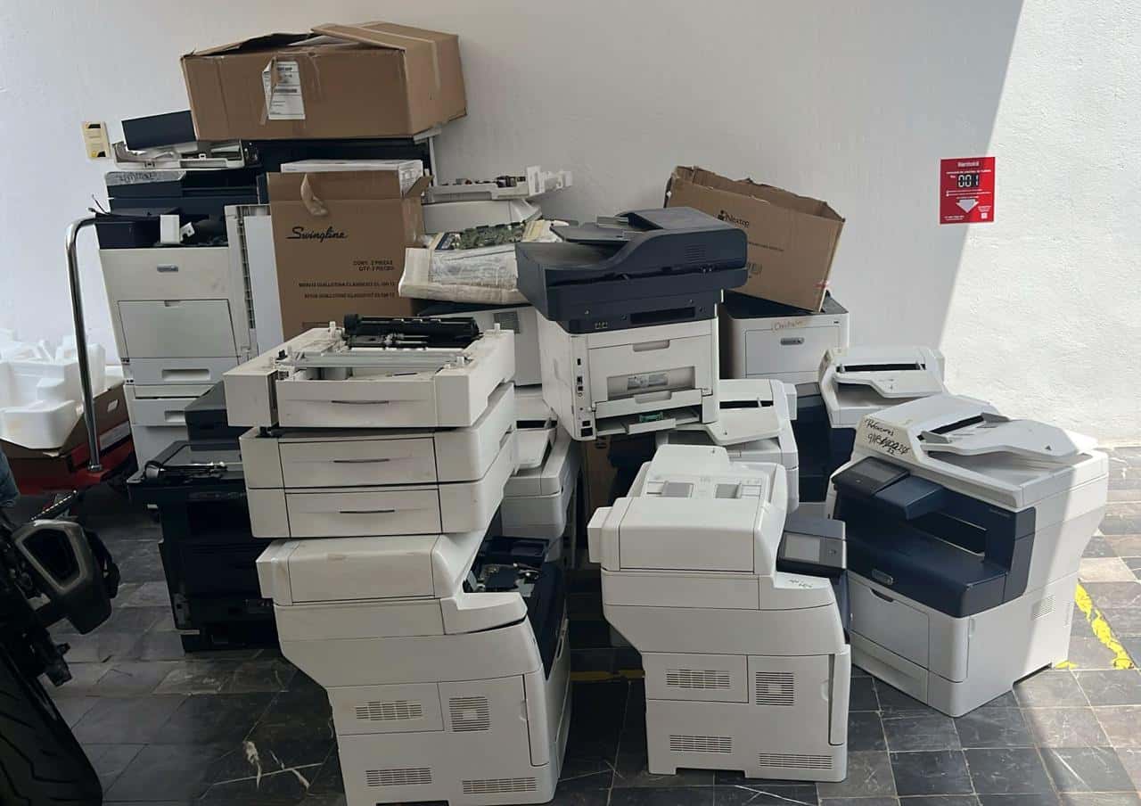 Impresoras multifuncionales y copiadoras acumuladas en una oficina antes de su reciclaje