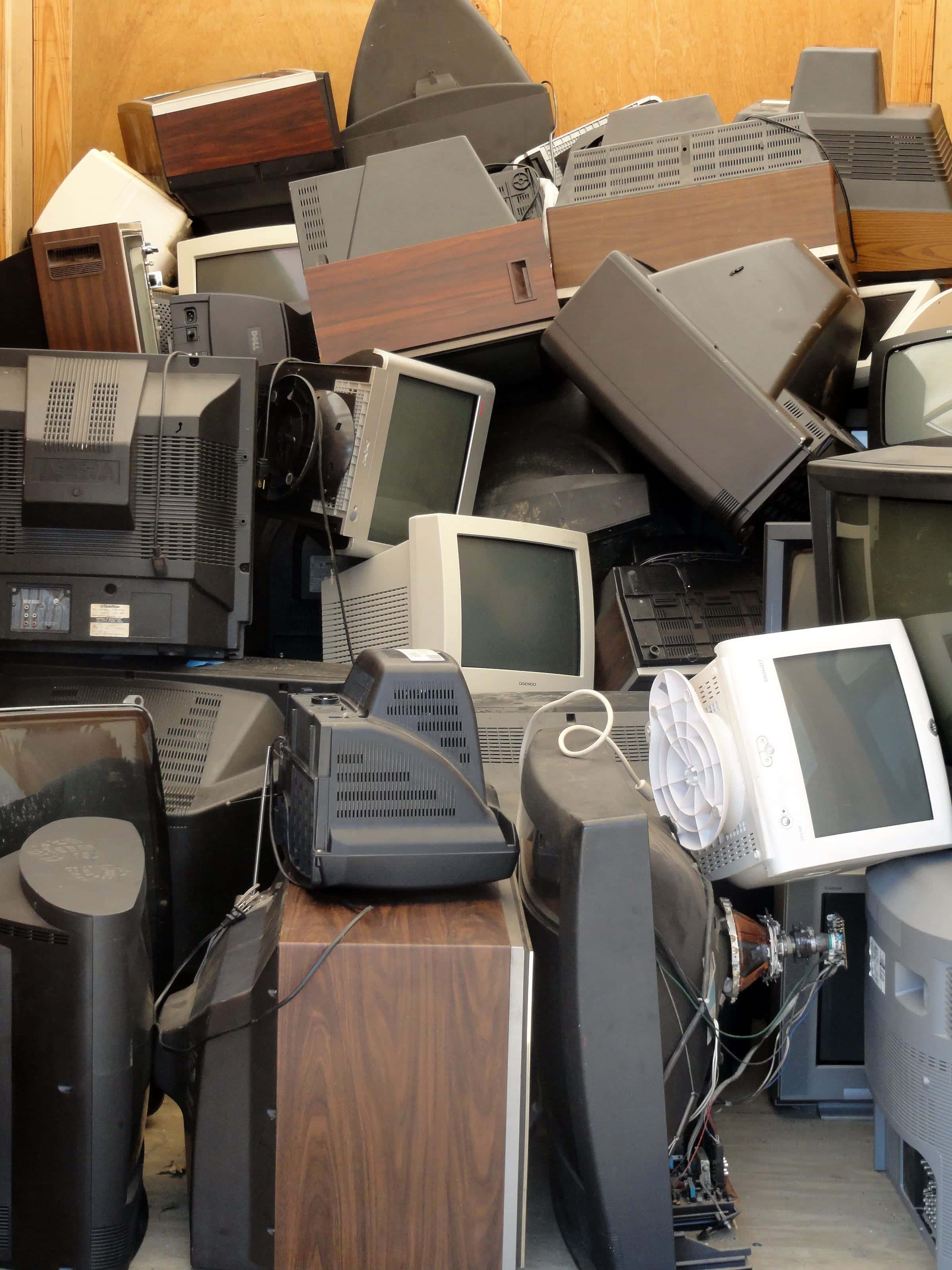 Monitores, televisores y aparatos electrónicos en desuso amontonados en una bodega