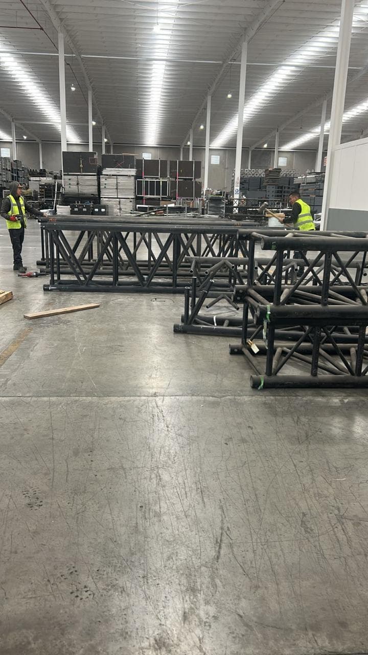 Personal con chaleco de seguridad realizando maniobras con estructuras metálicas en una bodega industrial
