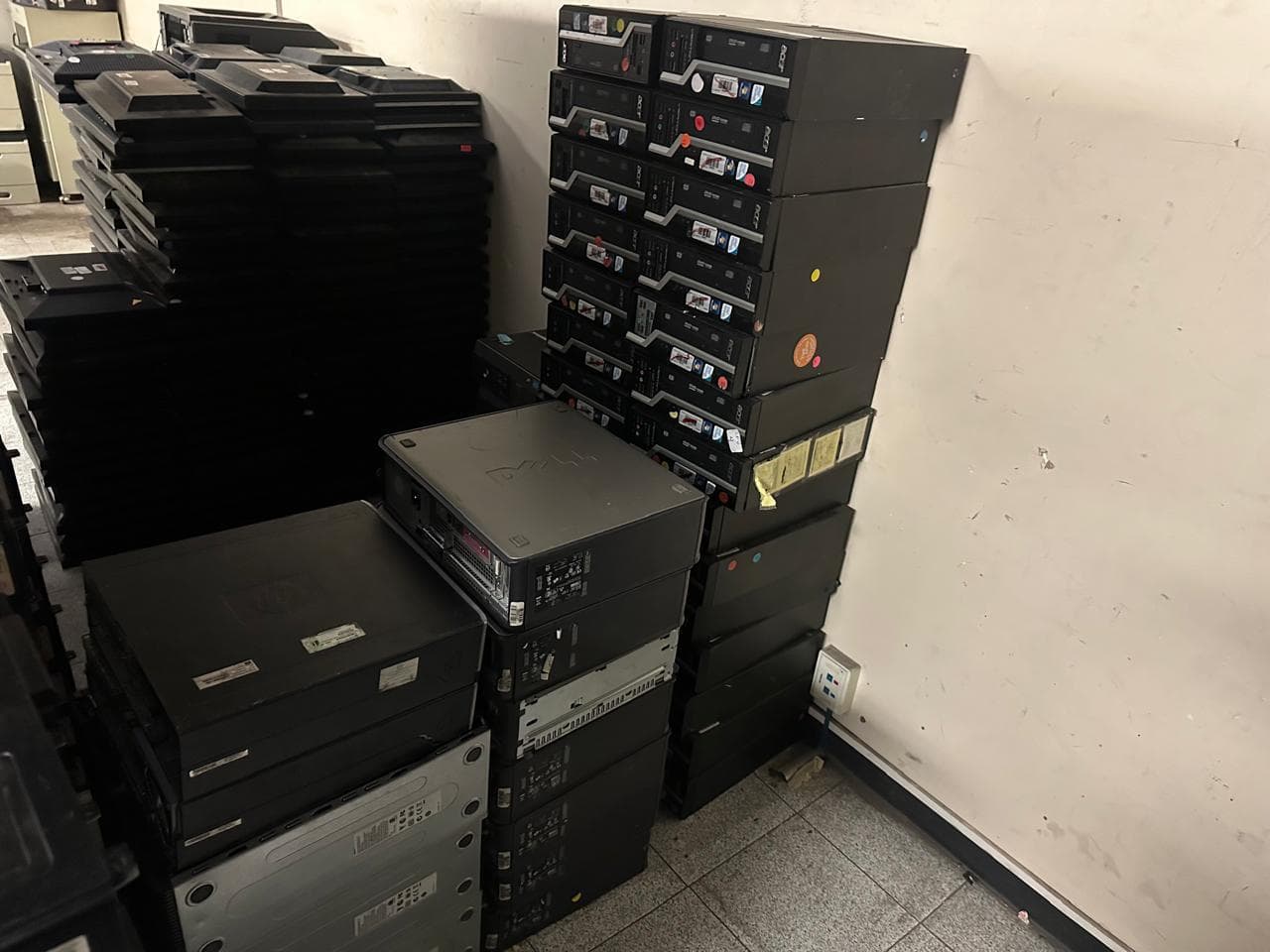 Computadoras de escritorio apiladas en una oficina, listas para la recolección empresarial